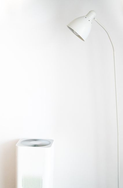 An air purifier standing against a wall, the kind of device that needs an activated carbon stage to actually pull VOC gases out of the air.