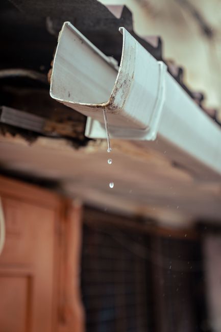 Water draining from a house gutter, the kind of drainage path that needs to stay clear and pointed away from the foundation.